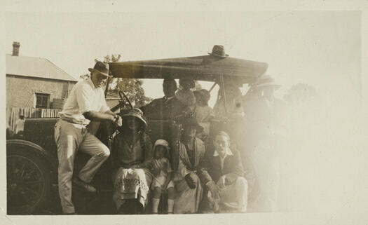 Ted Shumack, Eddie Edwards and Fred Cox with group of people and a car, at the Ainslie Cricket Ground. Taken from Yass Road, now Ellenborough Street.