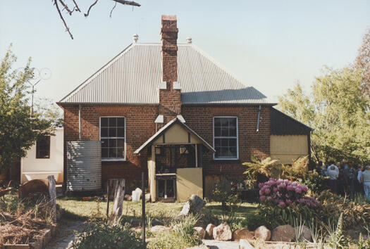 CDHS excursion to Tuggeranong showing a rear view of the schoolhouse residence. People are standing and sitting in the shade.