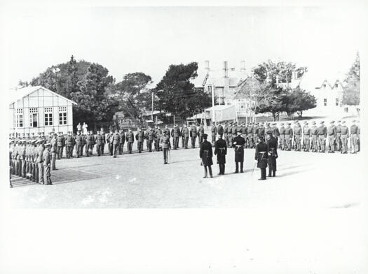 Approximately 120 soldiers in a hollow square formation on the RMC Parade Ground, apparently being addressed by senior staff officers.