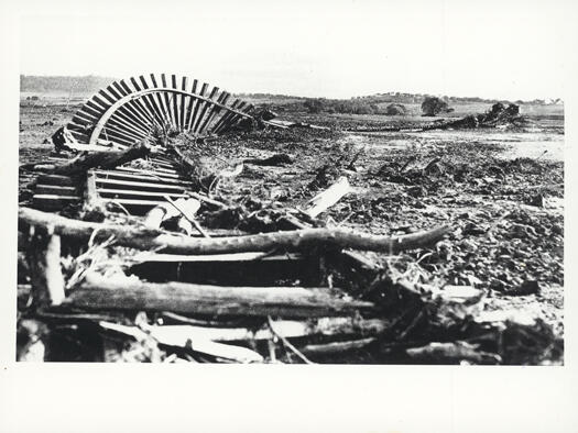Damage to railway lines caused by floods in 1925. Shows twisted railway lines covered in logs.