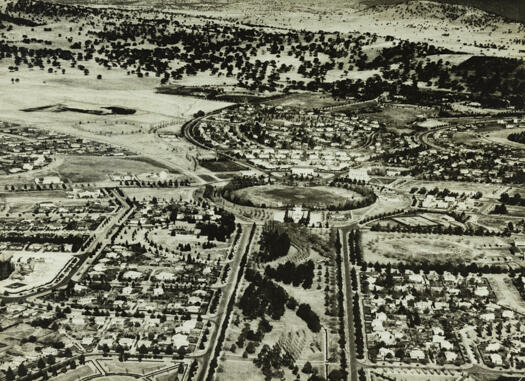 Aerial view over Telopea Park to Manuka Oval showing St. Christopher's Cathedral, Capitol Theatre, Telopea Park School, Manuka Swimming Pool, Captain Cook Crescent and Canberra Avenue.