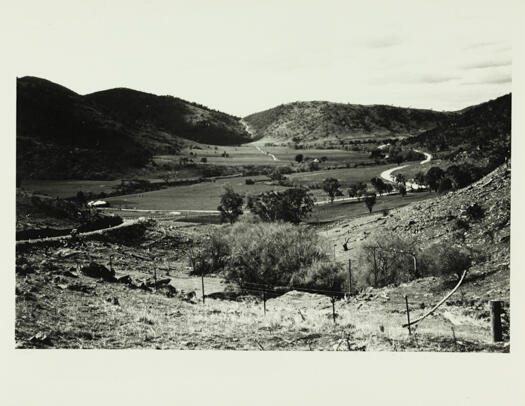 Photo of the Naas Valley taken from the Bobeyan Road at Fitz's Hill looking north. Shows the Gudgenby River and the farm buildings of Willow Vale and in the far distance a dirt road, Apollo Road, leading to Honeysuckle Creek.