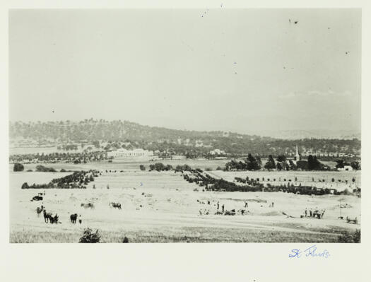 View from the Australian War Memorial site to Parliament House down what later became Anzac Parade. Men are at work on the site of the war memorial. The spire of St. John's Church can be seen to the right middle distance.