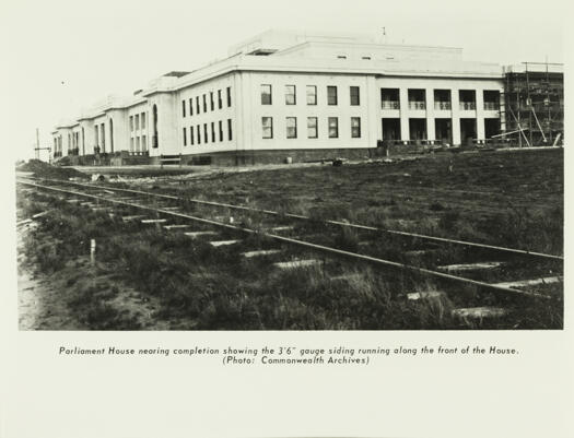 The almost completed Parliament House from the west end under construction with the 3 foot 6 inch gauge railway line running in front of the building.