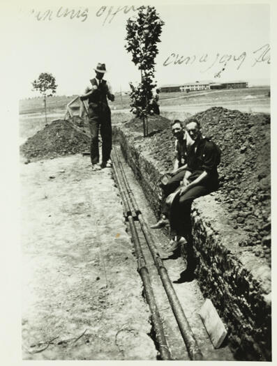 Tubes from Parliament House to Government Printing Office (which was in Wentworth Avenue, Kingston) being laid in a trench. Kurrajong Hotel can be seen in the midddle distance.