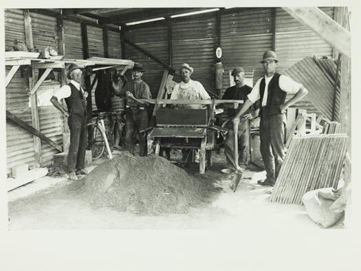 Four men and their foreman making concrete blocks in Acton. The blocks were for building purposes.