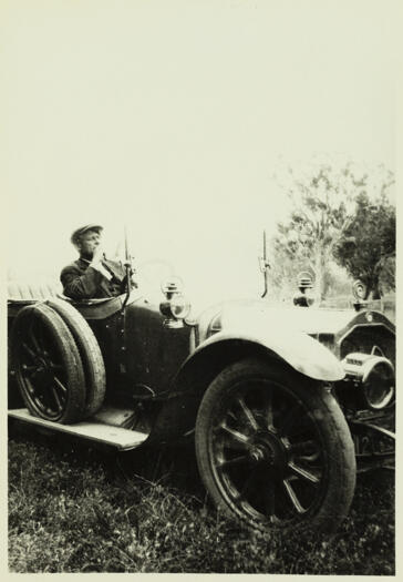 Early model car, possibly an Armstrong. An unnamed person is sitting in the car.