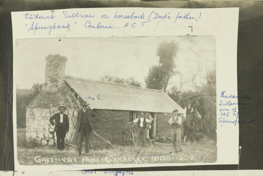 Postcard titled 'Greetings from Canberra 1908-1909'. It shows William Sullivan and Frederick Sullivan on horseback with three surveyors standing in front of a stone building.