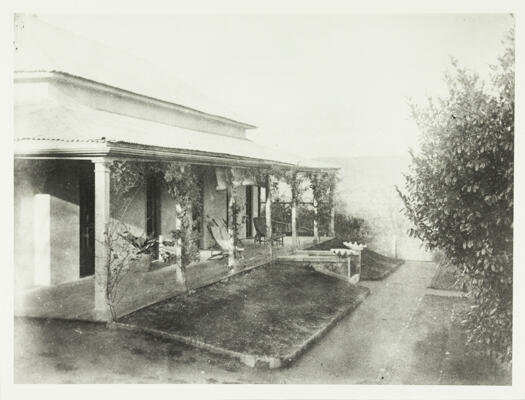 A right side frontal view of the verandah of Woden Homestead. Chairs can be seen on the verandah.
