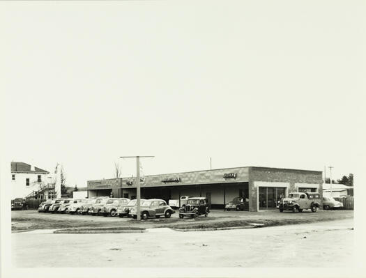 A front view of the garage of A.G. Mildren Ltd in Mort Street, Braddon. The photo includes signs for Castrol petrol and Morris cars.