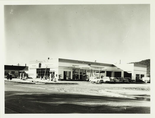 A front view of W.B. Freebody's garage in Braddon. A Mobil sign is visible and seven vehicles are parked in front.