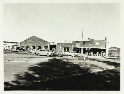 A side view of the Beazley and Bruce garage. At least 12 vehicles can be seen parked outside. COR (Commonwealth Oil Refinery) was the brand of fuel being sold.