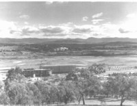 View from Mt. Pleasant showing the Russell Offices under construction. The Molonglo River can be traced by the trees in the middle of the photo. The Administration Offices and Parliament House are visible in the distance.
