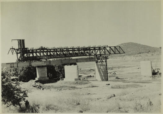 Kings Ave Bridge under construction. Shows a pre-stressed concrete beam on a gantry ready to be lowered.