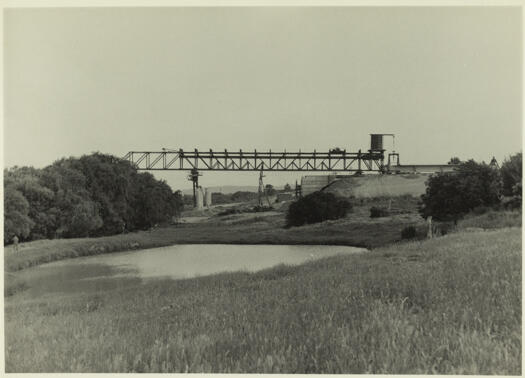 Kings Avenue Bridge under construction. A distant view looking east of a pre-stressed concrete beam entering the steel gantry.