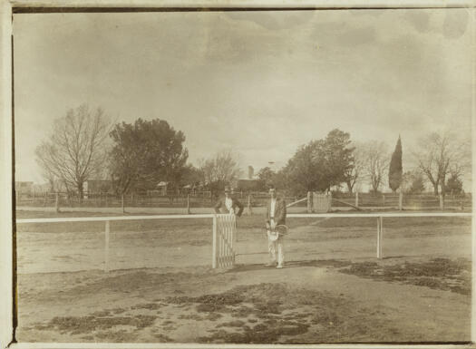 Acton House with two men dressed for tennis at the gate