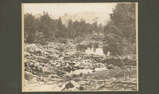 Cotter River with cleared hill in background. The river is not flowing though there are pools of water.