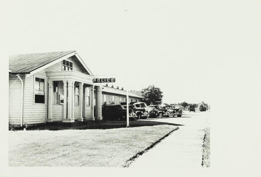 Police Station, Jolimont Building, Civic. Shows a wooden building with five cars parked out front. The lawn appears well maintained.