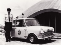 Constable John Franklin standing beside a Mini-Cooper 'S' police pursuit car. The Academy of Science and the ANU are in the background.