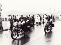 Police motor cycle escort of three motor bikes on a damp road. 