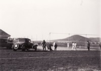 Players on the tennis courts at Braddon with six spectators and two cars parked nearby.