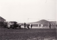 Players on the tennis courts at Braddon with six spectators and two cars parked nearby.