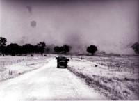 Bushfires in Canberra, 1952. Two fire trucks on the road and in the distance a cloud of smoke as the fire advanced.