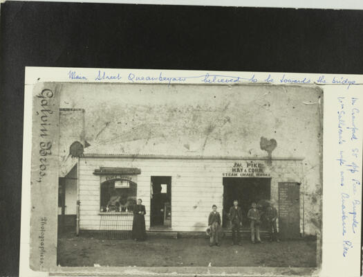 Shops in Crawford Street, Queanbeyan, opposite the Fire Brigade. Two shops are shown; Fancy Goods Shop and Pike's Hay & Corn shop, with three men and boy standing in front.