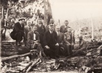 Early Federation party. Group of ten unidentified men, dressed in suits and sitting on logs in the bush.