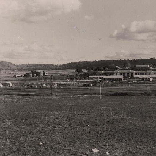 Parliament House and Administration Building under construction. A railway line runs at the front.