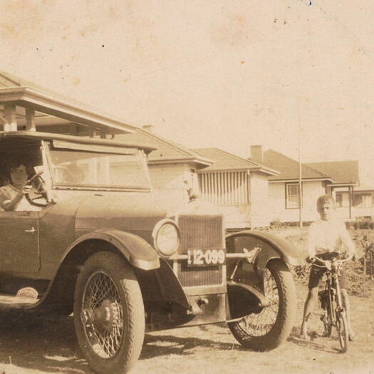 Rose Hunt's family photos showing a car (registration 12-099) with a woman in the driver's seat in the driveway of a house. A boy on a bicycle is near the front wheel.