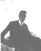 Tom Nicholls sitting on a bunk in a tent with a newspaper at Acton.