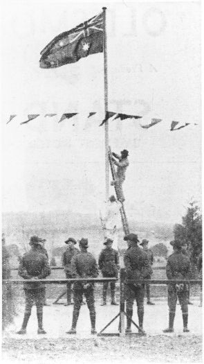 Parliament House - finishing touches. A man is on a ladder leaning against a flagpole which is surrounded by soldiers.