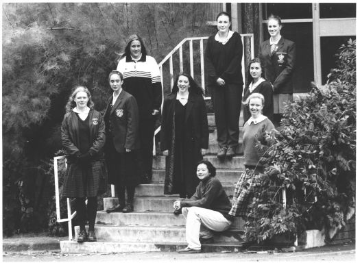 Canberra High School winter school uniform survey showing eight girls standing on steps at the school and one sitting