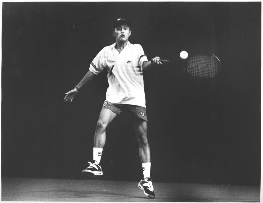 Left handed Vietnamese tennis player hitting a ball