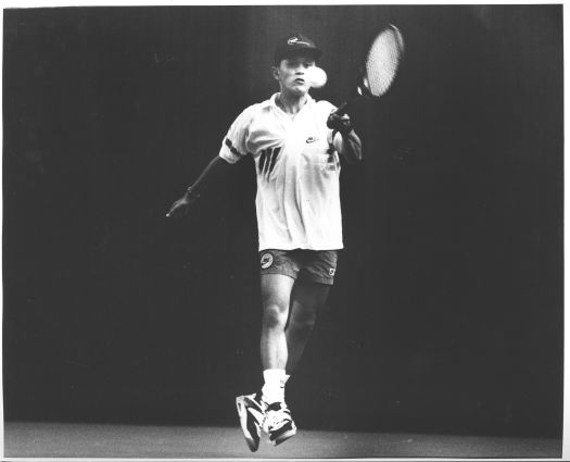 Left handed Vietnamese tennis player hitting a ball