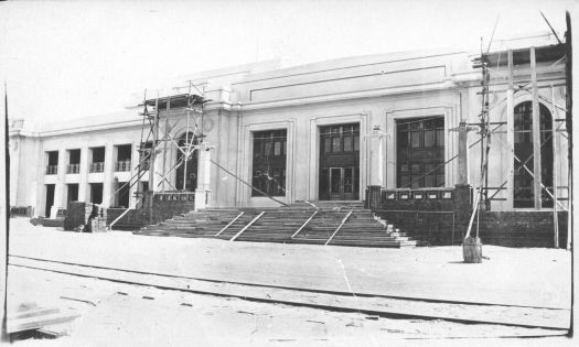 Parliament House nearing completion, railway in foreground past the front steps