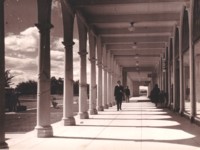 Two men walking along a footpath near the Sydney Building. A woman and a small girl are nearby. A sign reads \"Chief Electoral Office\".