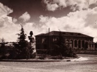 A front view of Albert Hall showing the curved gravel driveway and the statue of Bellona