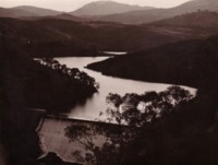 Photo shows the Cotter Dam wall with water backed up following the contours of the hills.