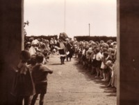 A photo of Santa Claus walking through lines of children at Ainslie School