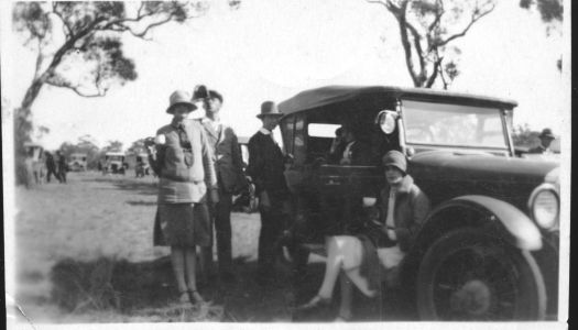 Six people standing around their car having a drink at the opening of Parliament House.