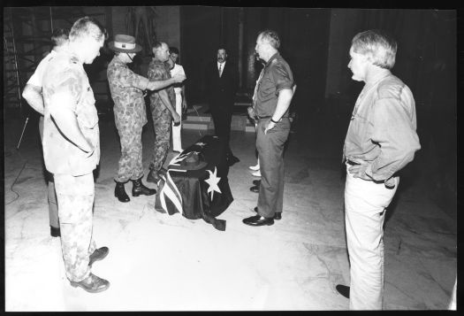 Coffin of the Unknown Soldier with Australian Flag and slouch hat on the coffin. Army personnel looking on.