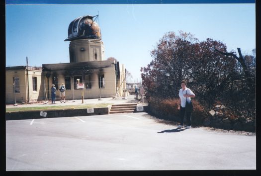 Judith Stubbs in front of bushfire damaged observatory at Mt Stromlo