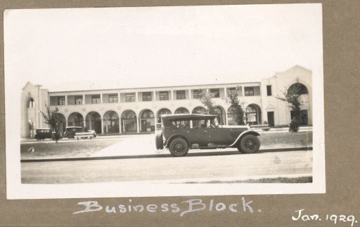 Part of a building with cars parked along the curb. Either the Sydney or Melbourne Building.