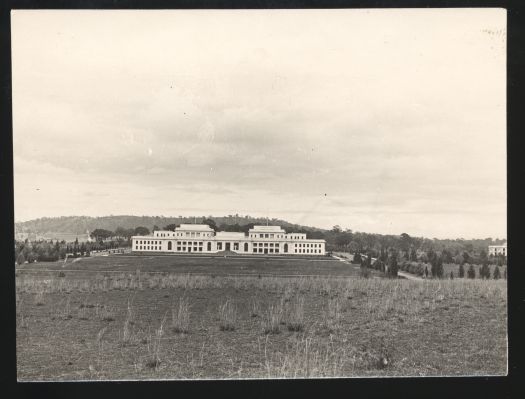 A distant view of old Parliament House with two cars parked in front