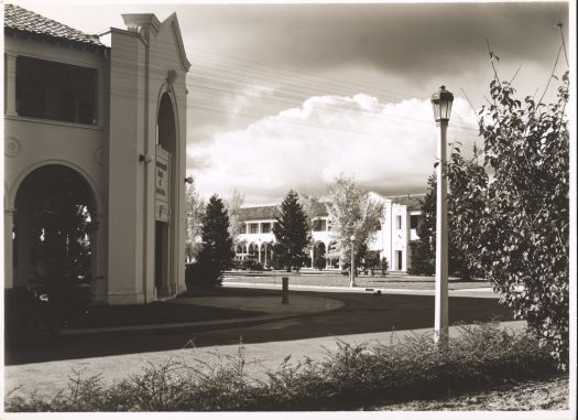 Corner of Melbourne Building and Northbourne Avenue looking towards the Sydney Building. A lamp post is in the foreground and a bus is outside the Sydney Building.