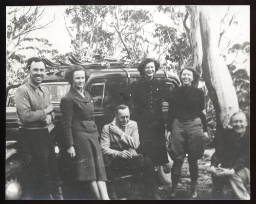 John Cumpston, Margaret Cumpston, Helena Galliott, Flo Asworth, ? Lane Poole, one person unknown, standing in front of a car with skis on the roof