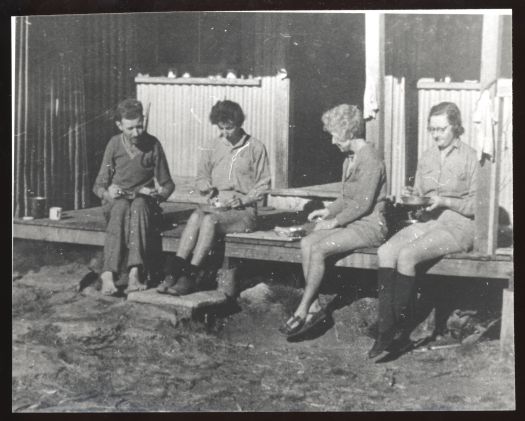 Moulder Harrison, Pam Page, Dorothy Hasluck, Edna Gassard eating on the verandah of Foremans Hut (now demolished).