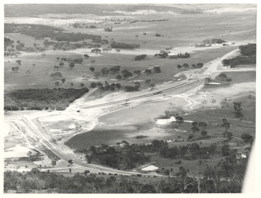 View from Black Mountain to the west towards Coppins Crosssing. Shows William Hovell Drive under construction, Glenloch cork plantation, Glenloch interchange and Caswell Drive. The site of the future suburb of Whitlam is visible.